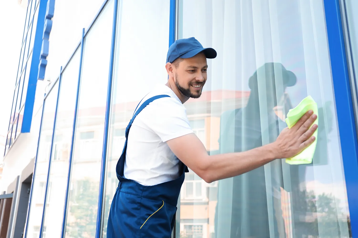 Männlicher Arbeiter beim Waschen von Fensterglas von außen 